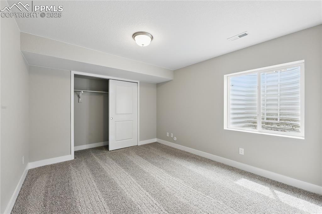 Image 31 of 35: Unfurnished bedroom featuring carpet floors, visible vents, a closet, and b