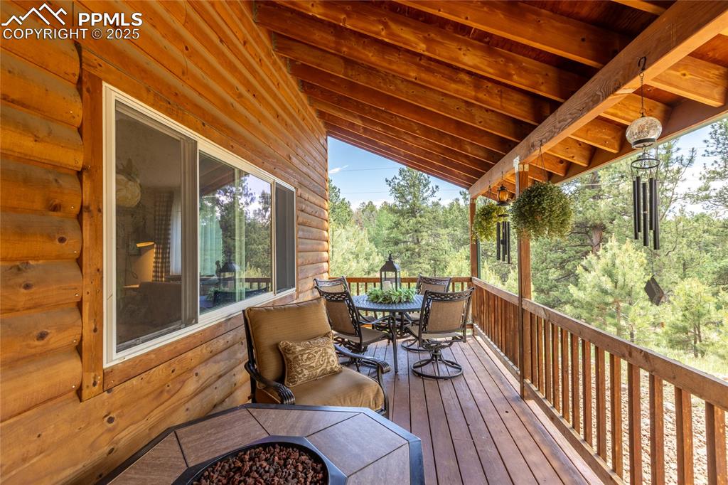 Image 2 of 50: Wooden terrace featuring outdoor dining space and a fire pit
