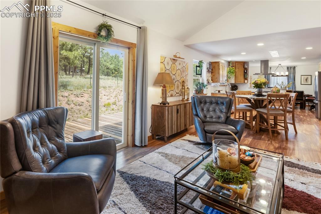 Image 26 of 50: Living room with wood finished floors, lofted ceiling, recessed lighting, a