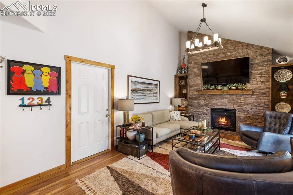 Image 29 of 50: Living room featuring a fireplace, wood finished floors, a chandelier, and