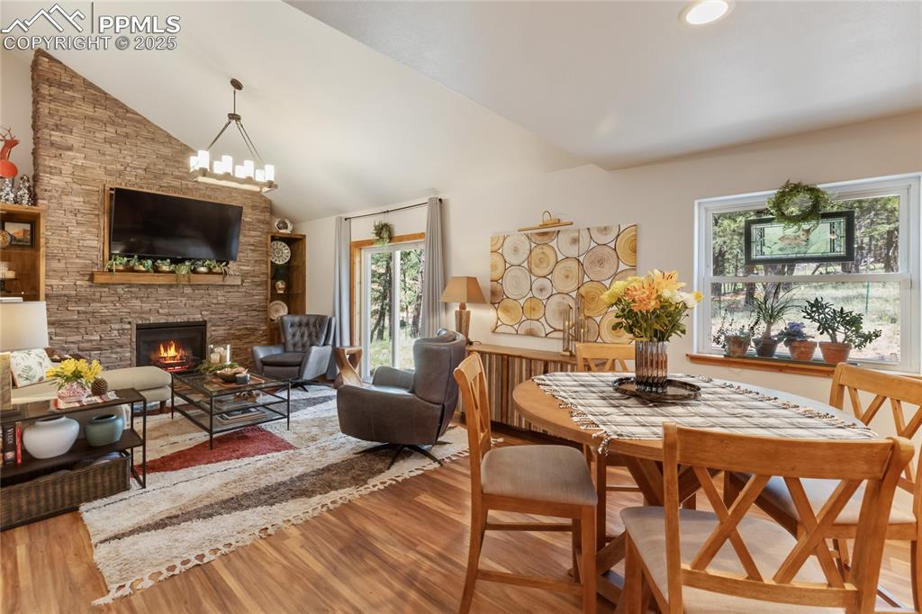 Image 31 of 50: Dining space featuring wood finished floors, a fireplace, lofted ceiling, a
