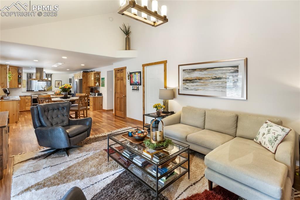 Image 32 of 50: Living area featuring light wood-type flooring, high vaulted ceiling, and r