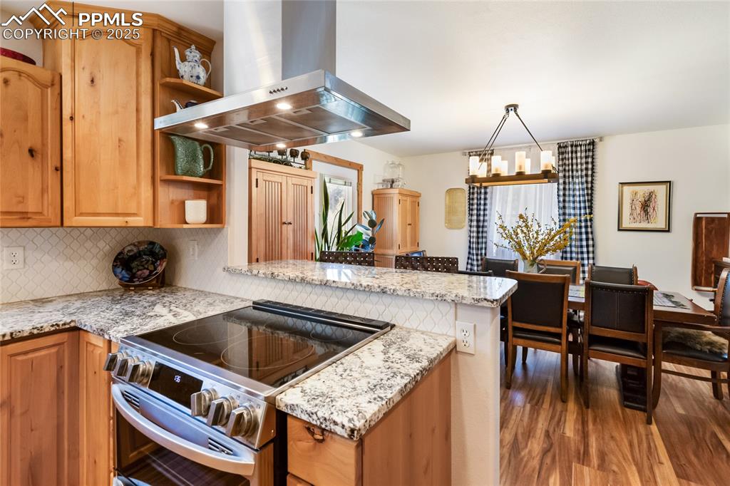 Image 36 of 50: Kitchen with stainless steel range with electric cooktop, wall chimney exha