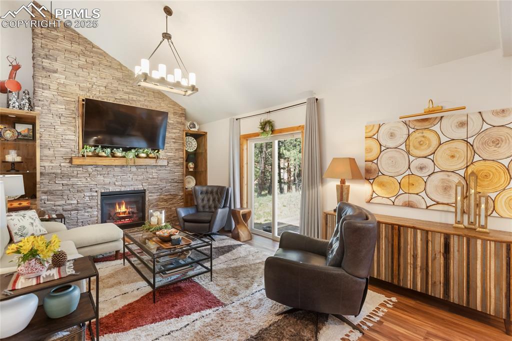 Image 4 of 50: Living area with wood finished floors, a fireplace, high vaulted ceiling, a