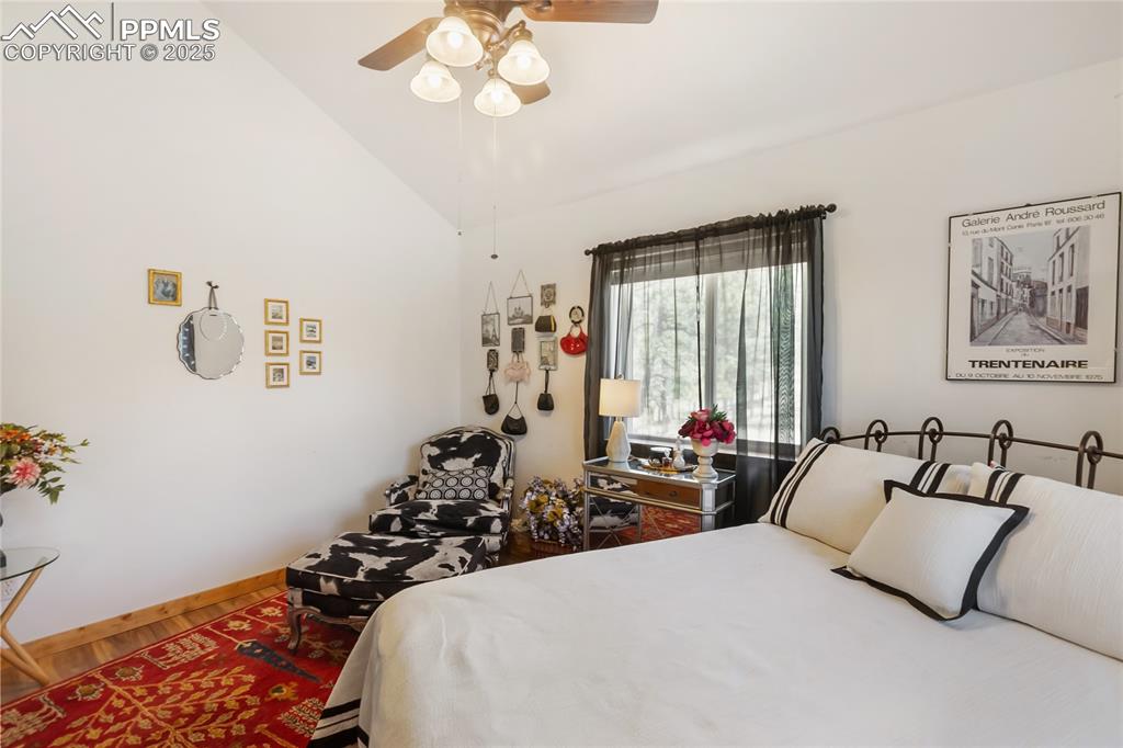 Image 44 of 50: Bedroom with vaulted ceiling, ceiling fan, and wood finished floors