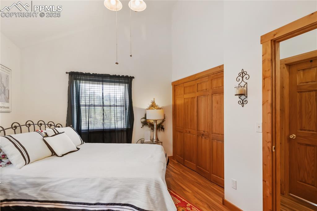Image 45 of 50: Bedroom with wood finished floors and high vaulted ceiling
