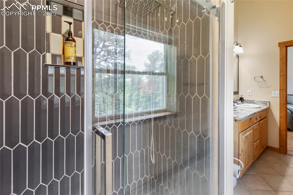 Image 48 of 50: Bathroom with vanity, a tile shower, and tile patterned floors