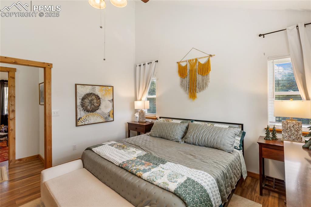 Image 49 of 50: Bedroom with wood finished floors and a high ceiling