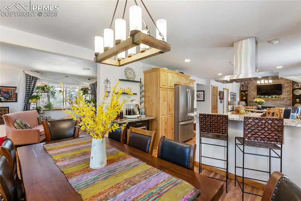 Image 6 of 50: Dining space with light wood-style floors and recessed lighting