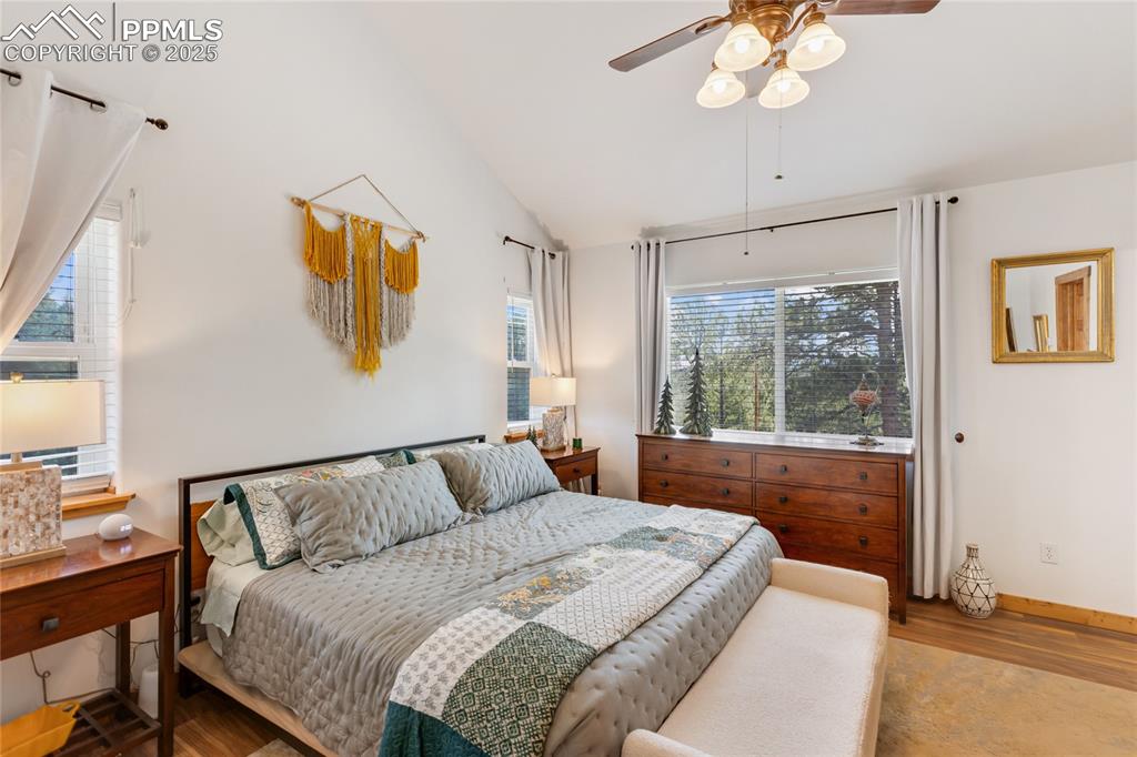 Image 8 of 50: Primary bedroom featuring multiple windows, vaulted ceiling, wood finished