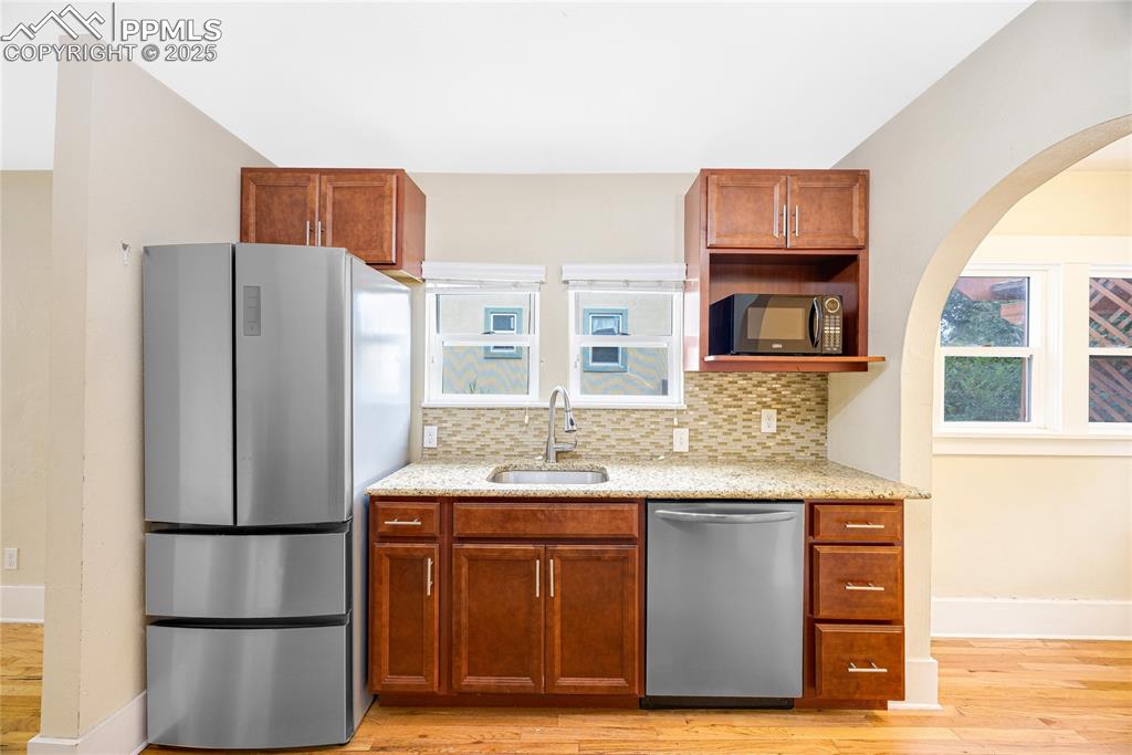 Image 10 of 28: Kitchen featuring appliances with stainless steel finishes, light stone cou