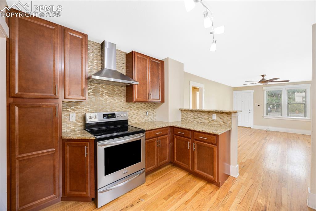 Image 11 of 28: Kitchen featuring backsplash, stainless steel range with electric cooktop,
