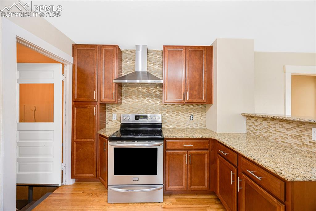 Image 12 of 28: Kitchen featuring tasteful backsplash, brown cabinetry, stainless steel ran