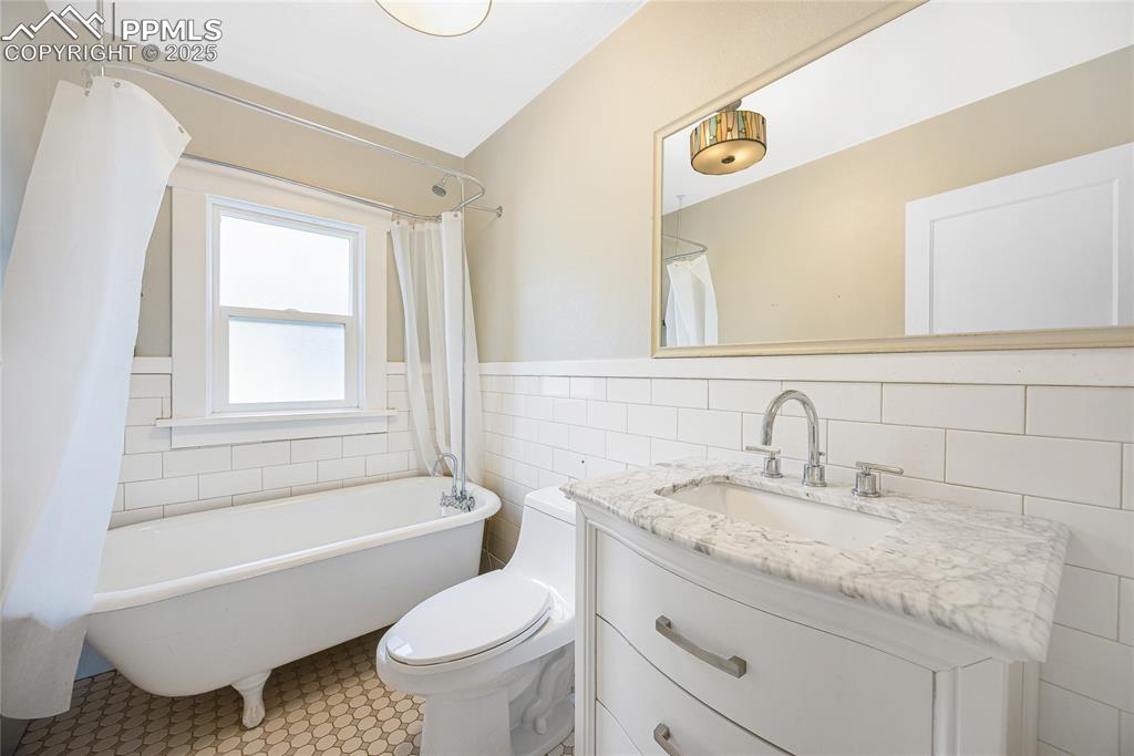 Image 17 of 28: Bathroom featuring vanity, tile walls, a combined bath / shower with freest