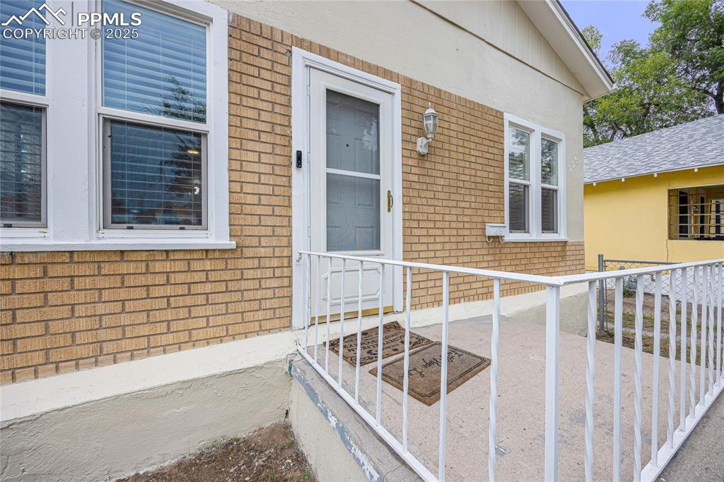 Image 4 of 28: Doorway to property featuring brick siding