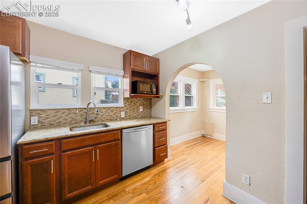 Image 9 of 28: Kitchen with arched walkways, stainless steel appliances, light stone count