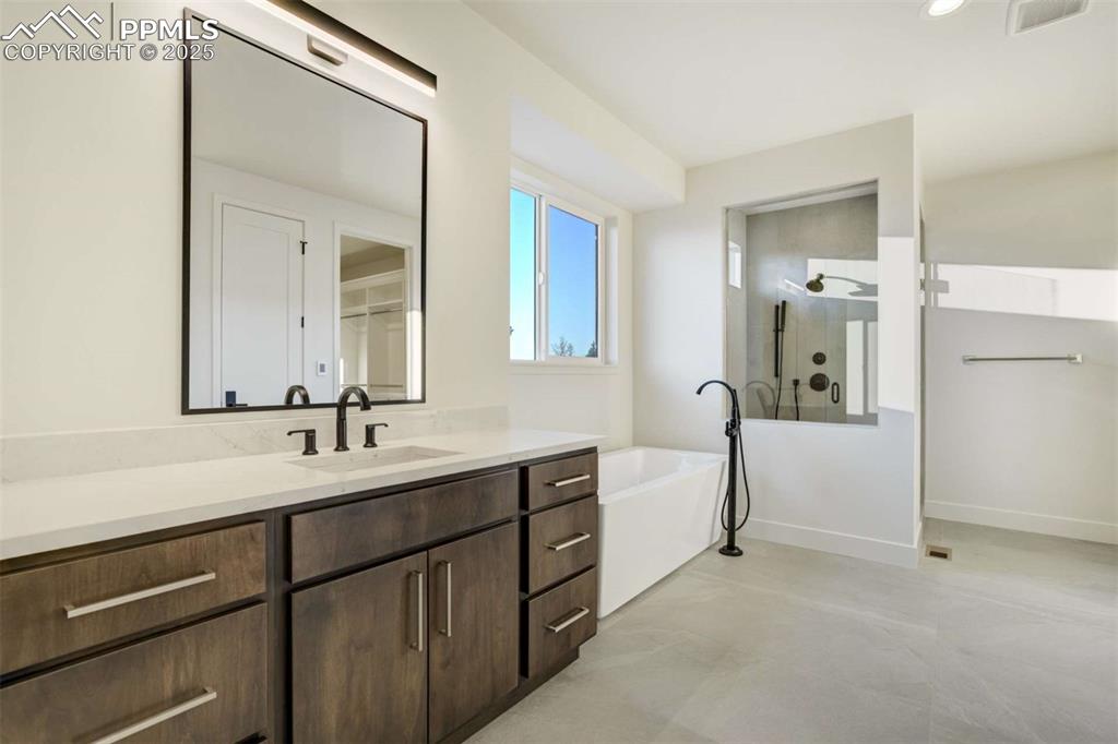 Image 15 of 34: Full bathroom featuring vanity, a stall shower, a freestanding bath, and re