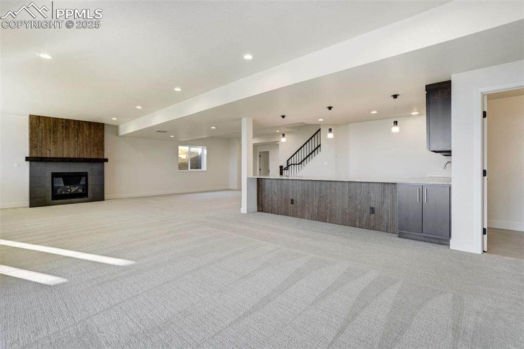 Image 22 of 34: Unfurnished living room with recessed lighting, light carpet, a large firep