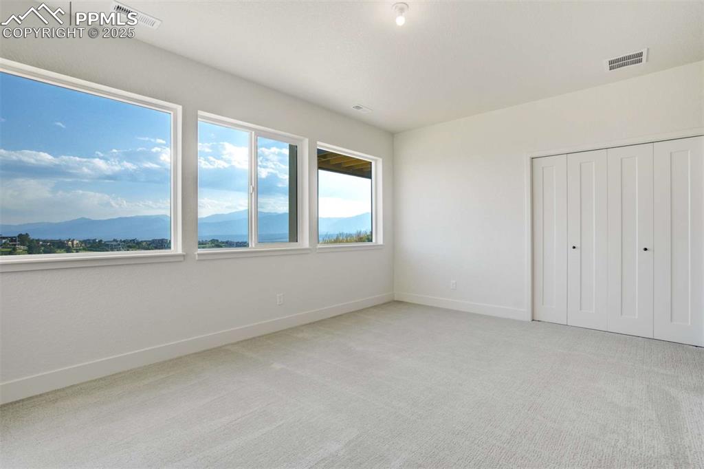 Image 26 of 34: Unfurnished bedroom with light colored carpet, a mountain view, and a close