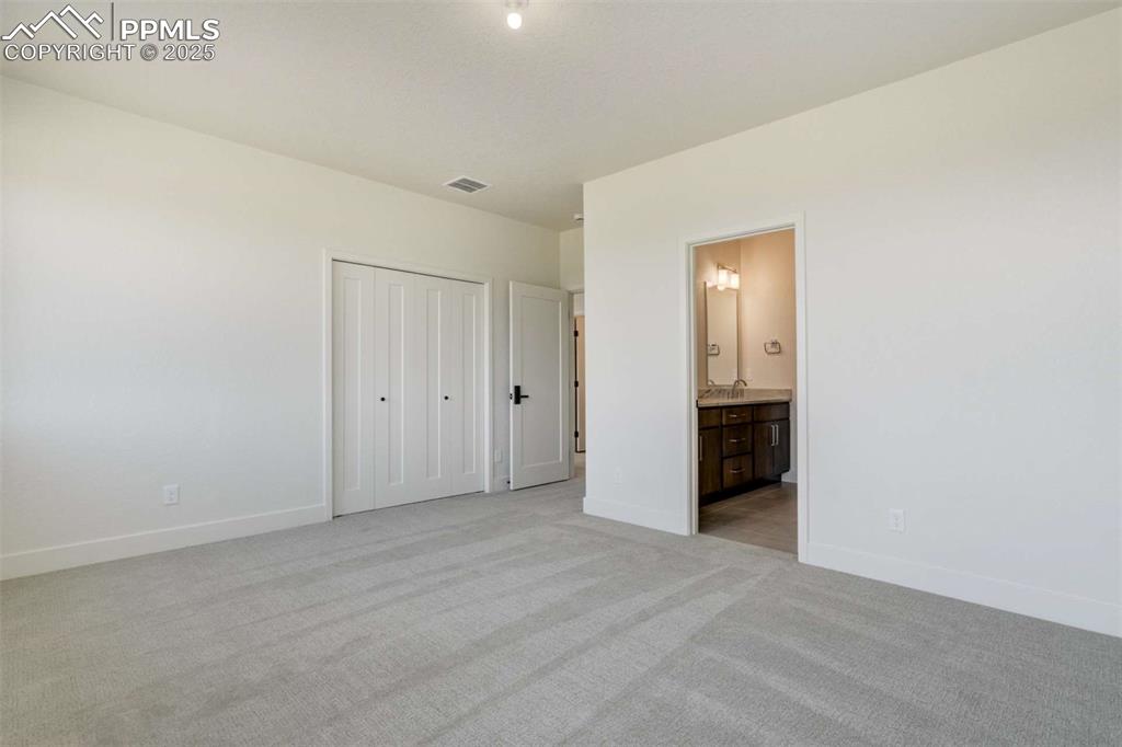 Image 27 of 34: Unfurnished bedroom with light carpet, connected bathroom, and a closet