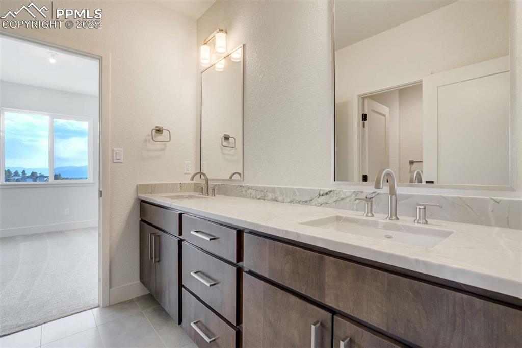 Image 28 of 34: Full bathroom featuring double vanity, light tile patterned floors, and a t