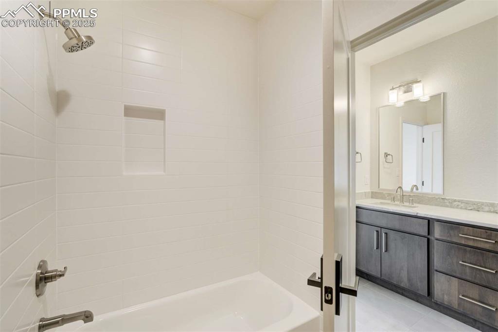 Image 29 of 34: Full bathroom with tub / shower combination, vanity, and light tile pattern