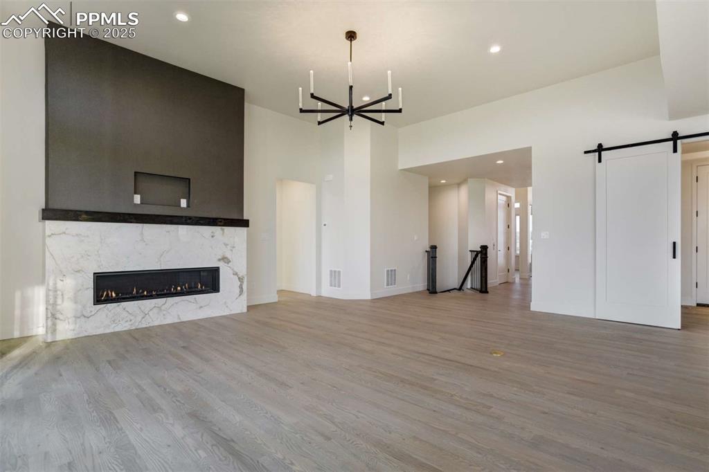 Image 6 of 34: Unfurnished living room with a barn door, recessed lighting, a high end fir