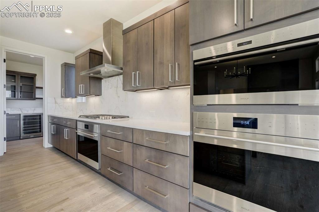 Image 9 of 34: Kitchen with stainless steel appliances, modern cabinets, range hood, wine