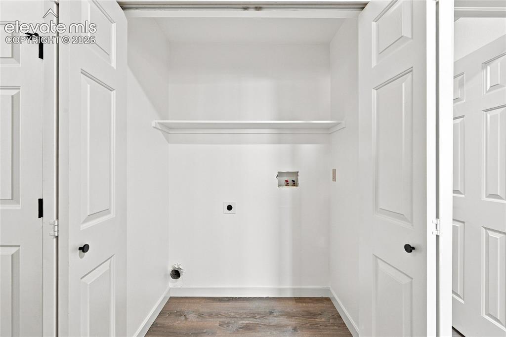 Image 10 of 30: Laundry area featuring a built-in shelf, white paneled bifold doors, and wo