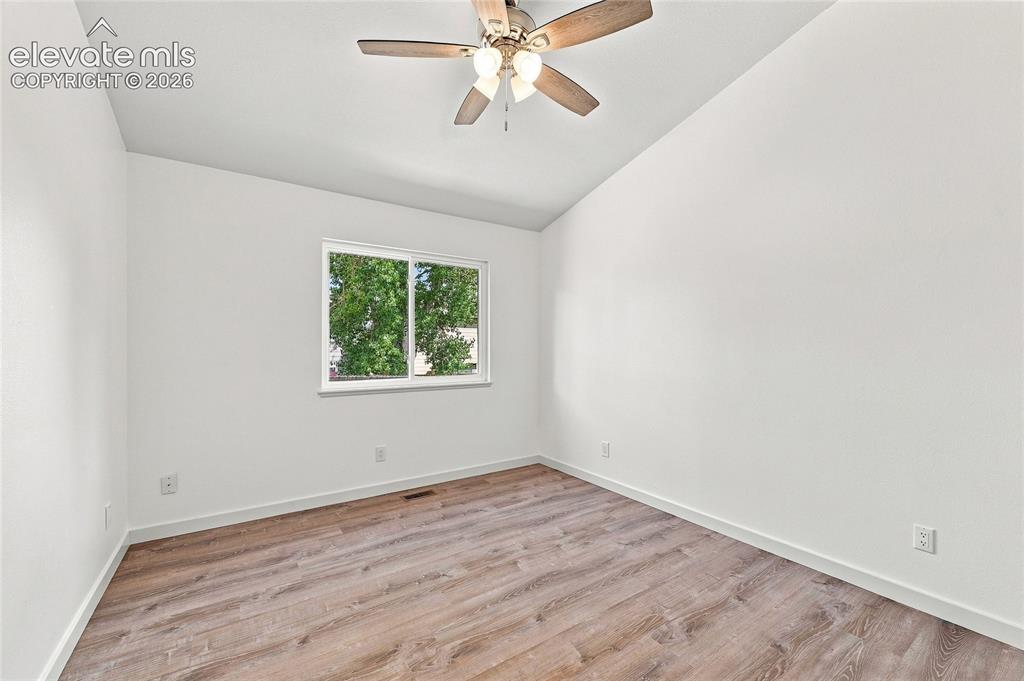 Image 11 of 30: Vaulted ceiling with a ceiling fan, wood-finish flooring, and a window prov