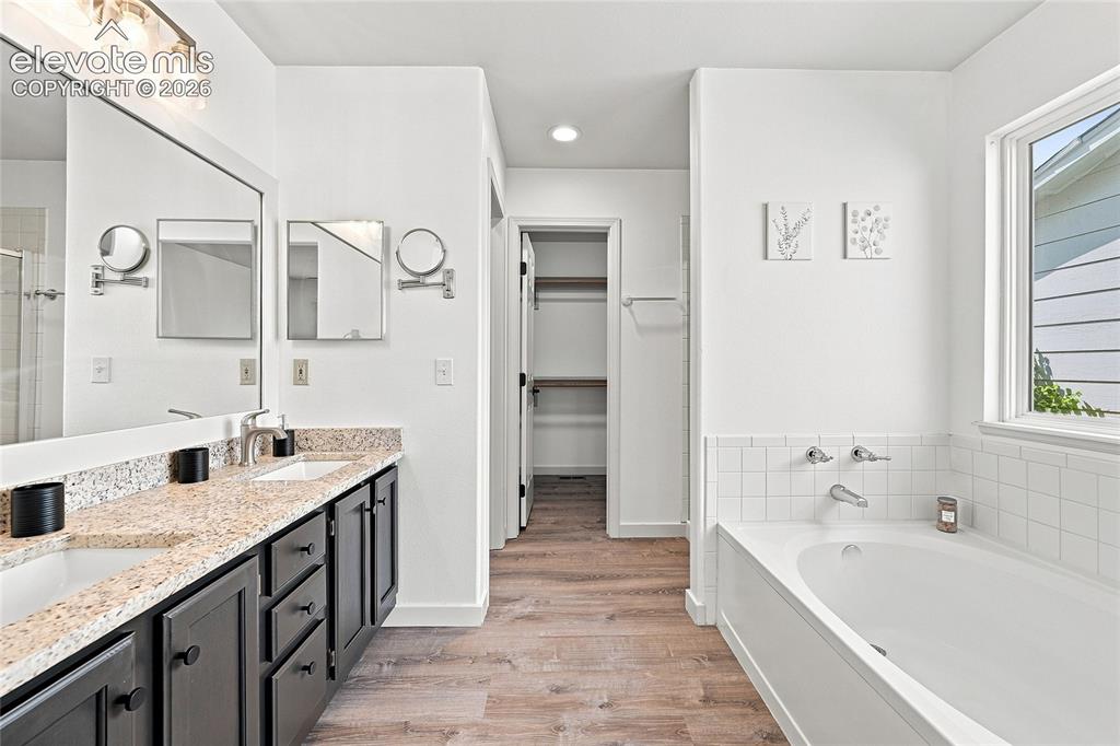Image 16 of 30: Dual vanity with granite-style countertops, wood-finish flooring, built-in 