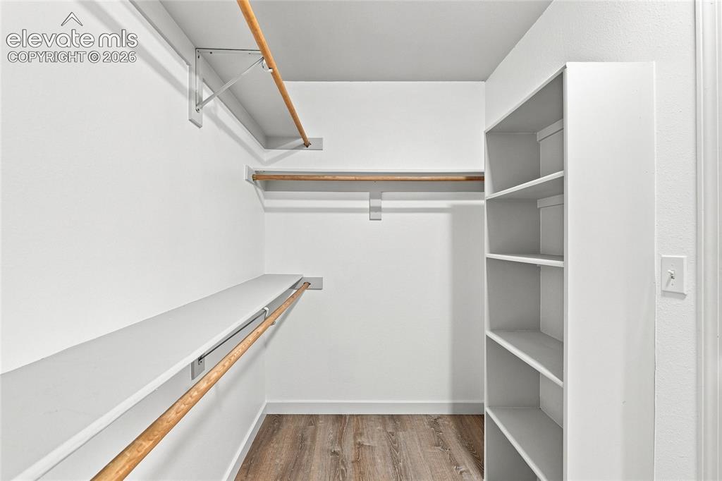 Image 18 of 30: Wood-finish flooring with white baseboards, built-in shelving, white walls,