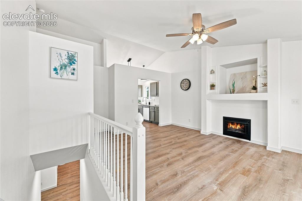 Image 6 of 30: Vaulted ceilings, wood-finish flooring, built-in fireplace, ceiling fan, an