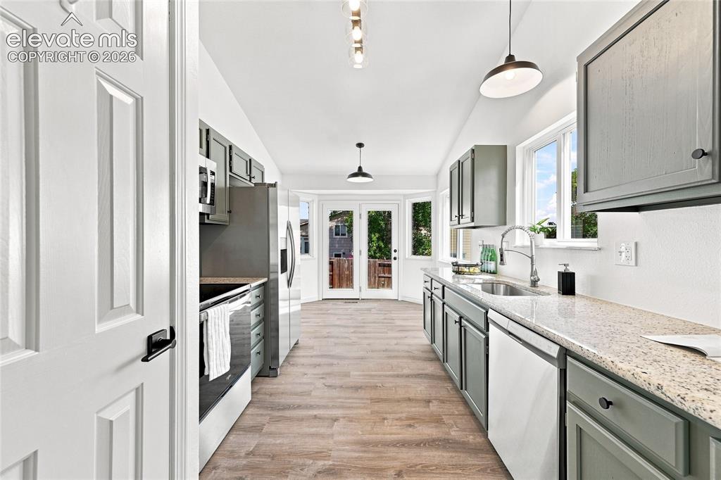 Image 7 of 30: Galley kitchen with wood-finish flooring, gray cabinetry, stainless steel a