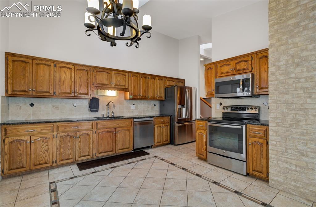 Image 3 of 45: Kitchen with stainless steel appliances, granite counters and custom tile f