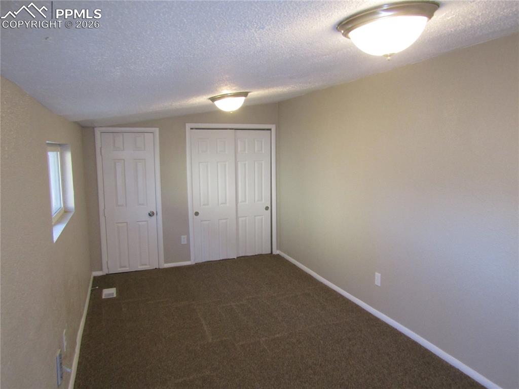Image 16 of 21: Unfurnished bedroom featuring a closet and dark carpet
