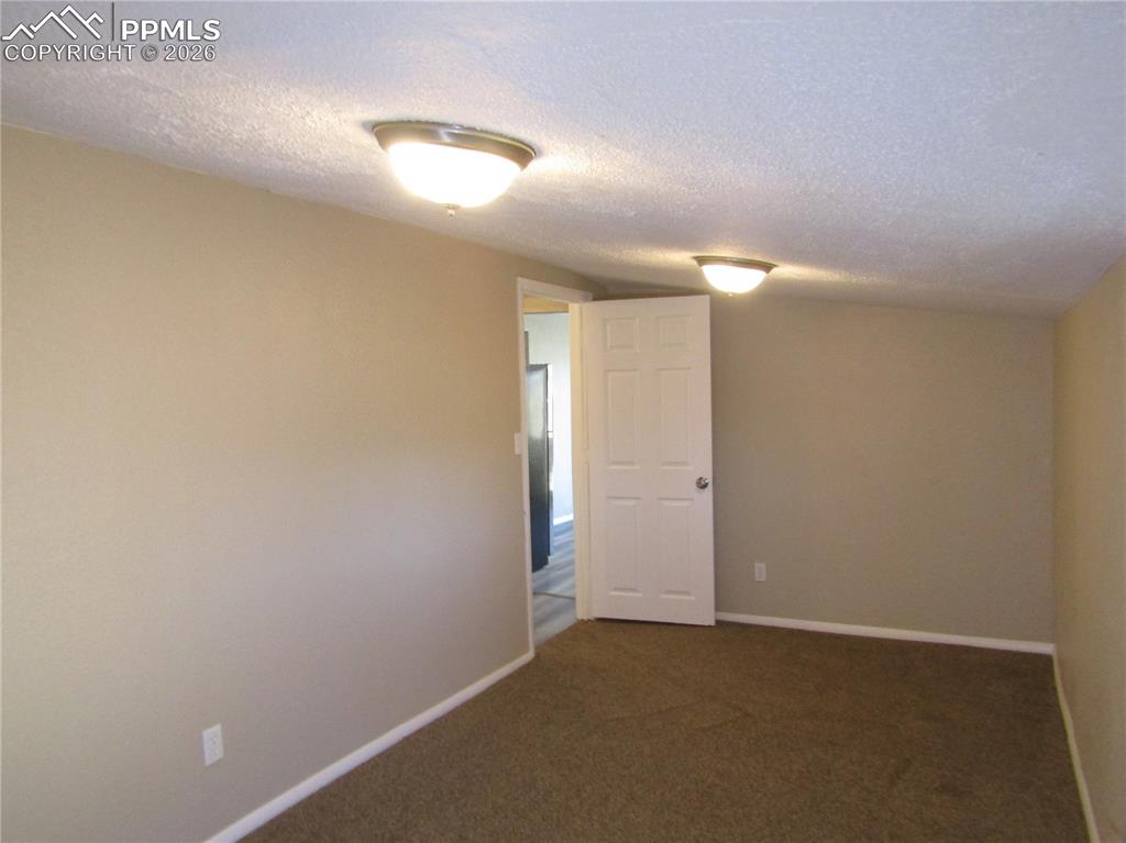 Image 17 of 21: Unfurnished room with a textured ceiling and dark colored carpet