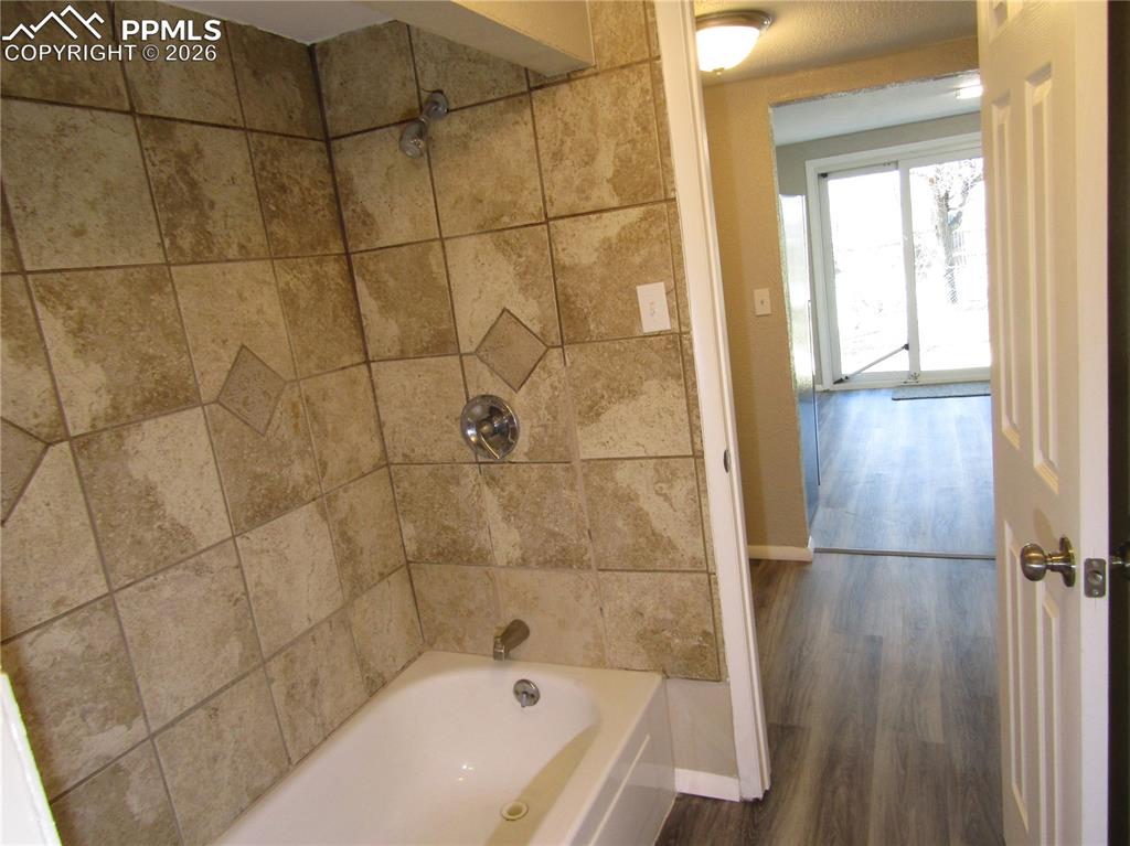 Image 20 of 21: Full bathroom featuring washtub / shower combination and dark wood-style fl
