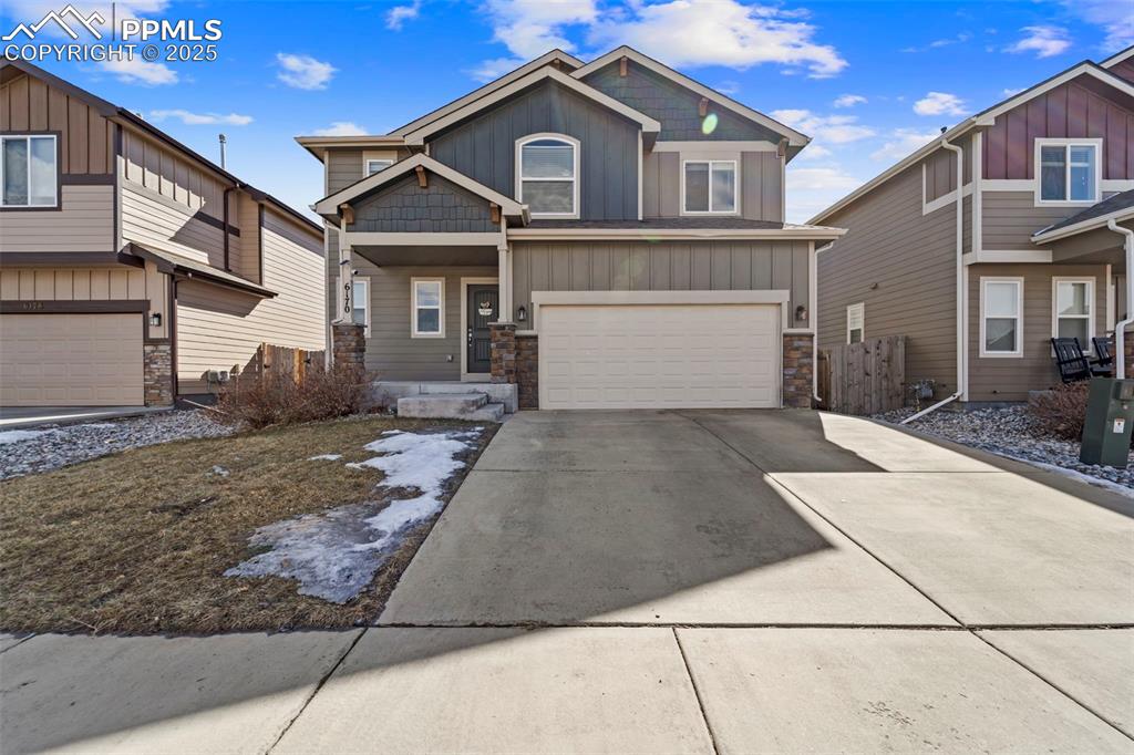 Caption: Craftsman-style house with board and batten siding, concrete driveway, stone siding, and an attached