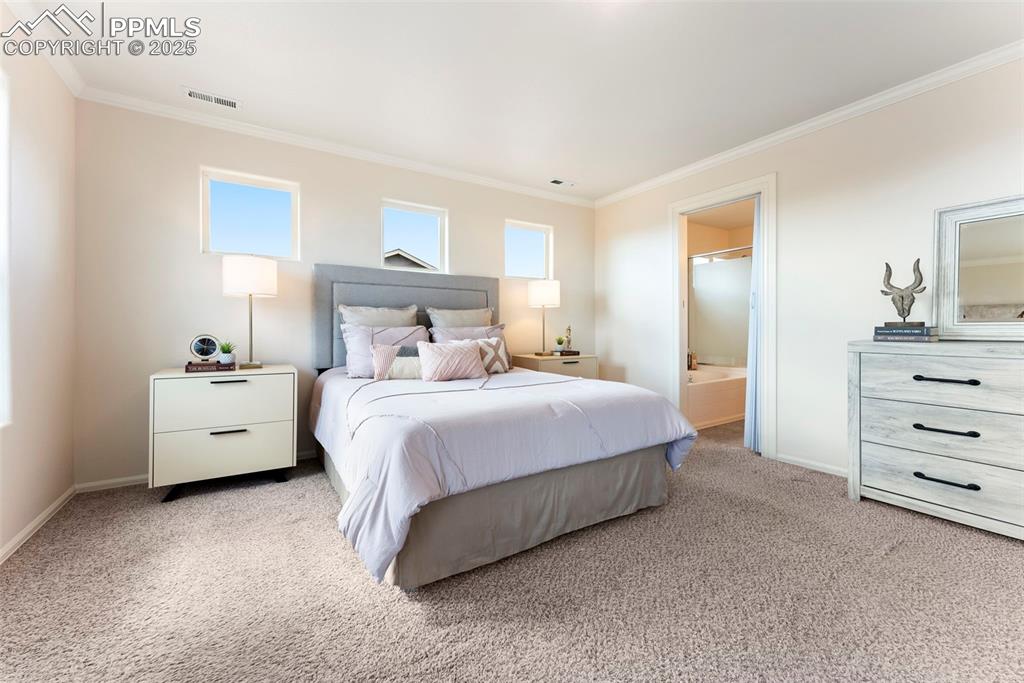 Image 14 of 50: Bedroom with carpet floors, crown molding, and ensuite bath