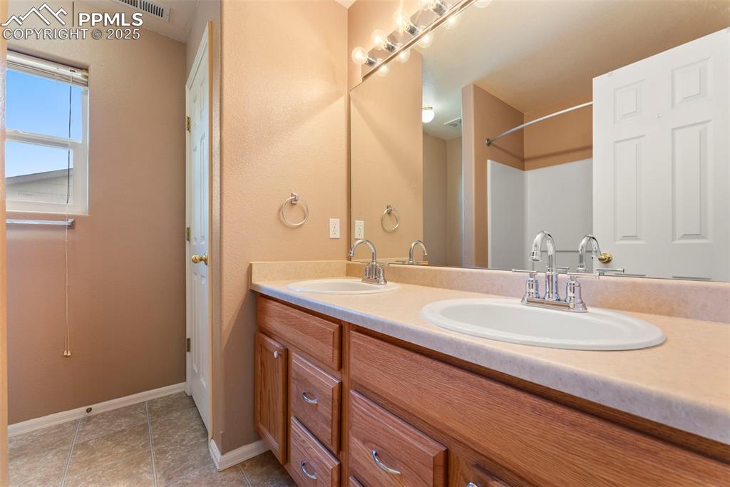 Image 23 of 50: Full bathroom featuring double vanity and light tile patterned flooring