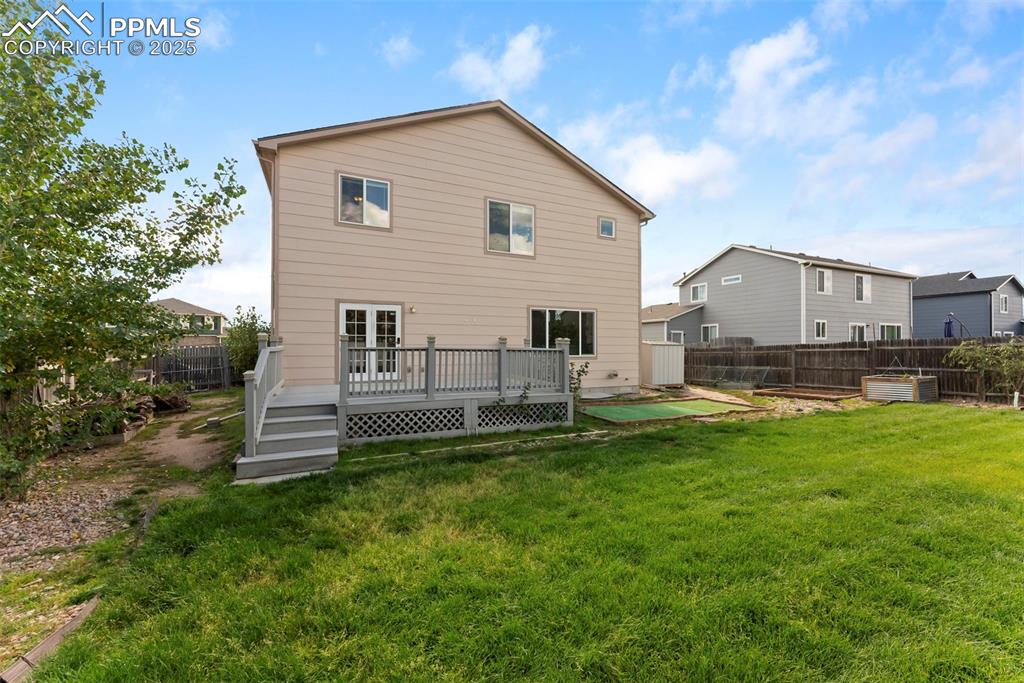 Image 35 of 50: Rear view of house featuring a fenced backyard and a wooden deck