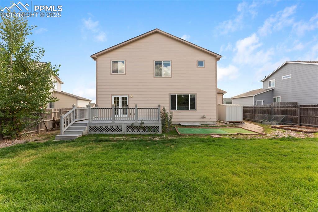 Image 36 of 50: Back of house with a fenced backyard and a deck