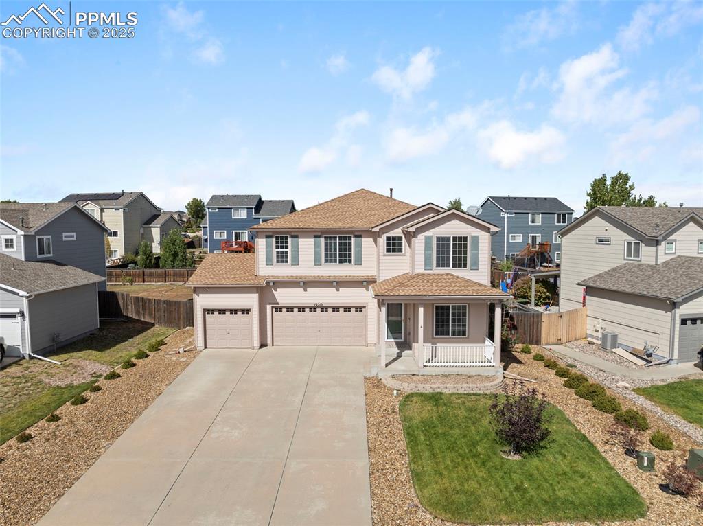 Image 42 of 50: Traditional home with driveway, a residential view, a porch, and roof with 