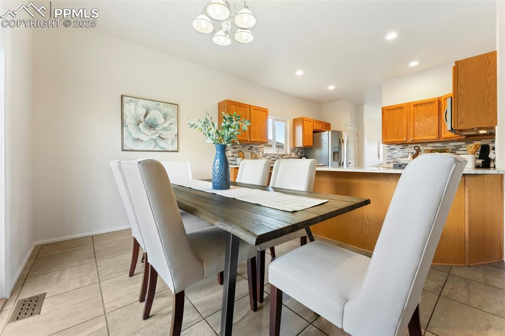 Image 7 of 50: Dining space with a chandelier, recessed lighting, and light tile patterned