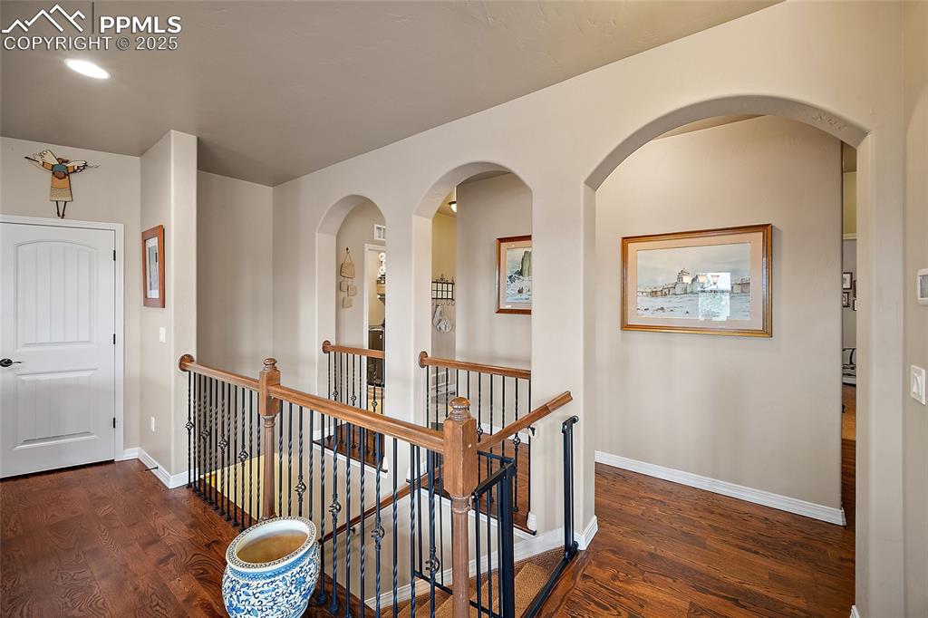 Image 14 of 39: Hall with an upstairs landing, dark wood finished floors, and arched walkwa