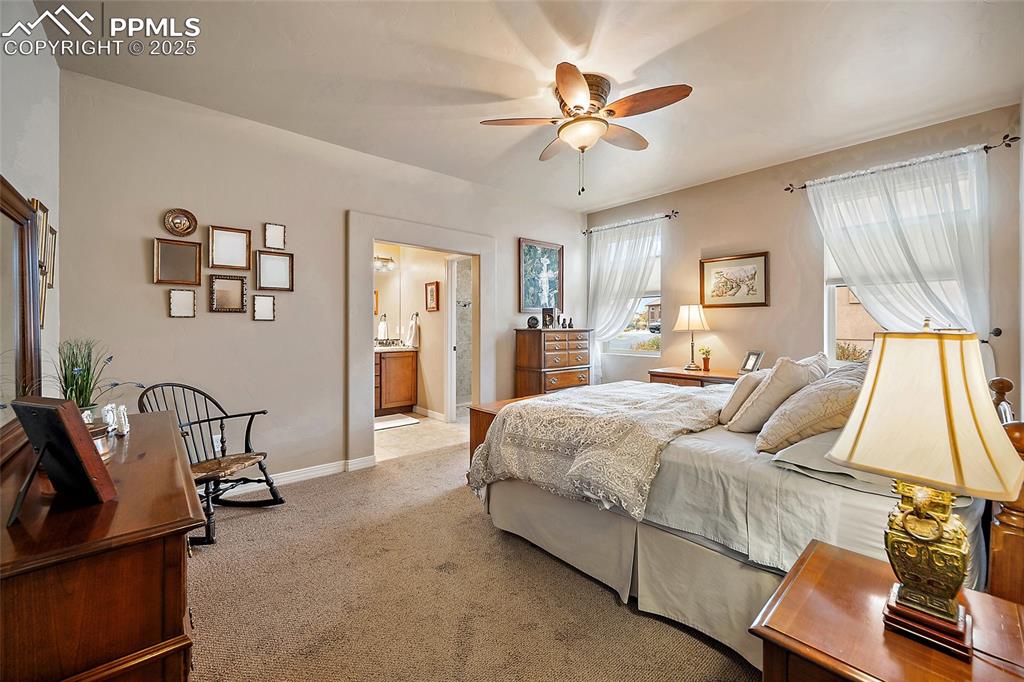 Image 15 of 39: Bedroom with light colored carpet, ensuite bathroom, and ceiling fan
