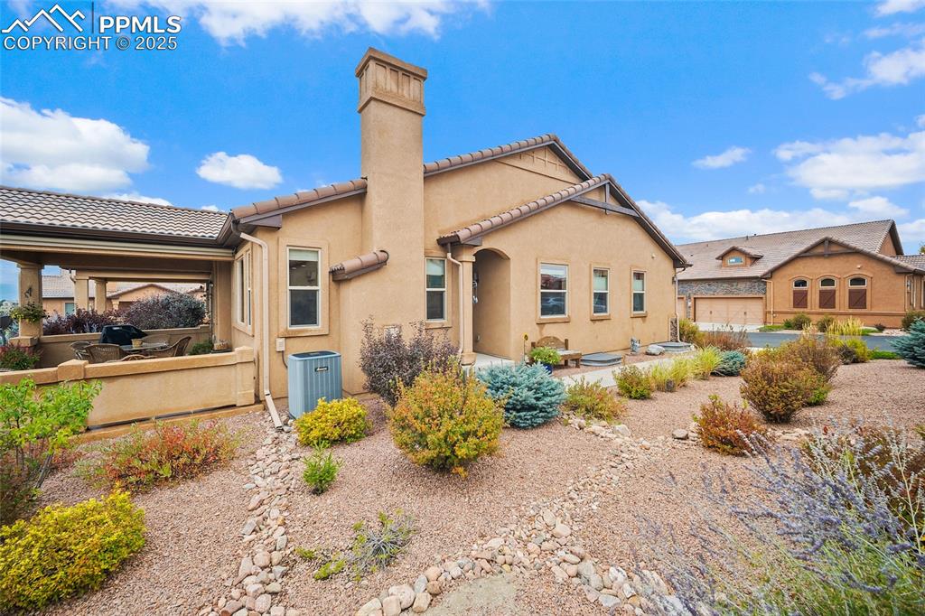 Image 32 of 39: View of side of property featuring stucco siding, a tile roof, and a chimne