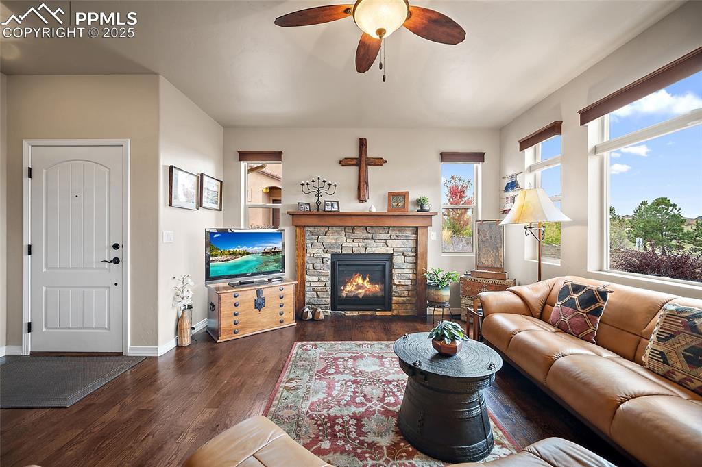 Image 5 of 39: Living area featuring a fireplace, dark wood-style flooring, and ceiling fa