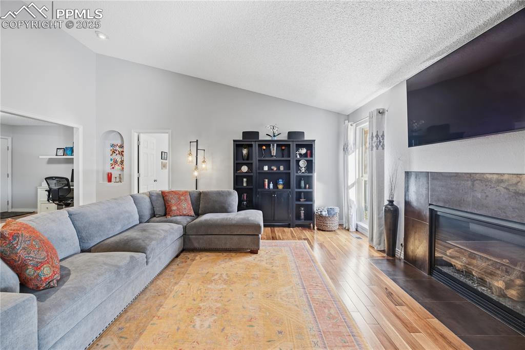 Image 10 of 50: Living area with hardwood / wood-style floors, a desk, a fireplace with flu